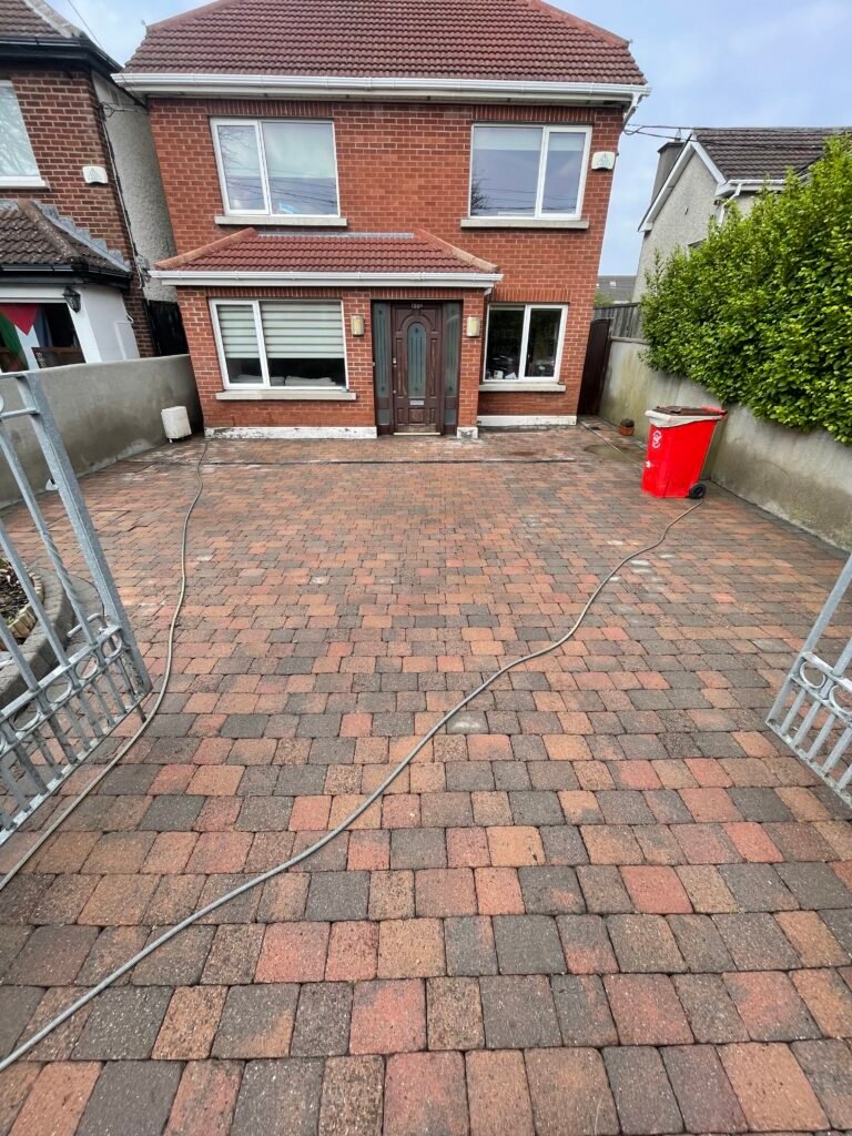Red and grey block-paved driveway after cleaning, with paving still wet
